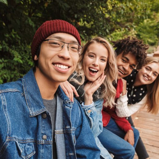Group if cheerful multiethnic friends teenagers spending fun time together outdoors, taking a selfie